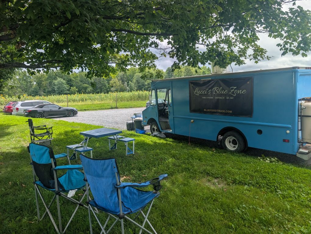 Camp chairs and picnic table set up next to the Big Blue Truck at Chatham Berry Farm